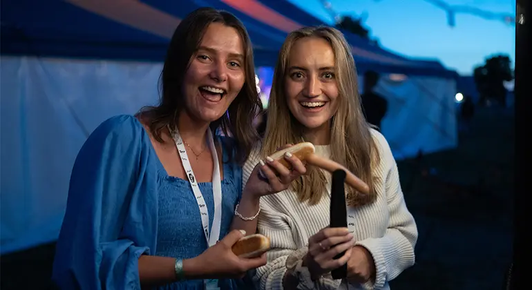 Två glada tjejer serverar korv på Torpkonferensen.